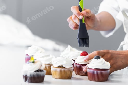 Preview: Crop cook smearing berries on cupcakes with syrup