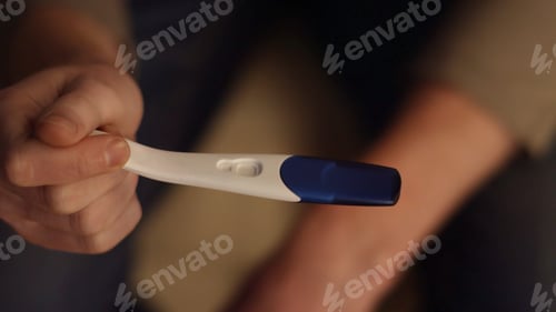 Preview: Male hand holding positive pregnancy test close up. Male hands holding a pregnancy test and put it