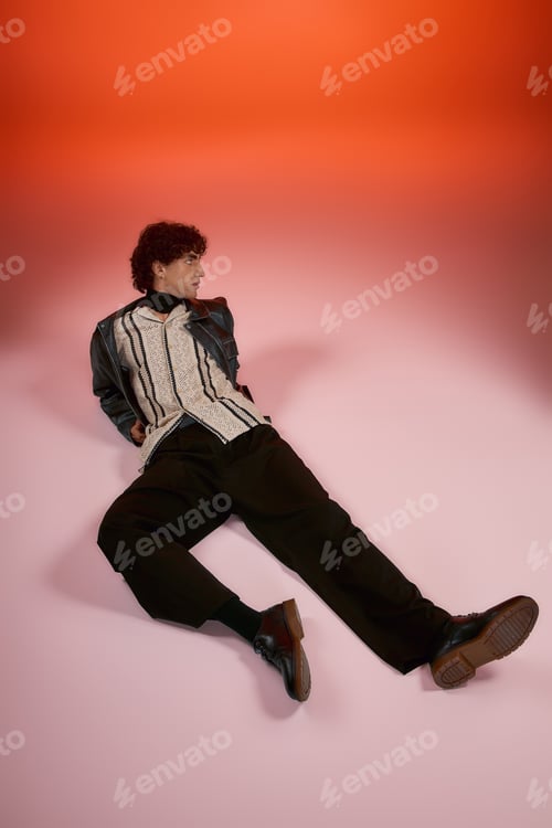 Preview: Stylish young man posing effortlessly on a colored background in a fashionable outfit