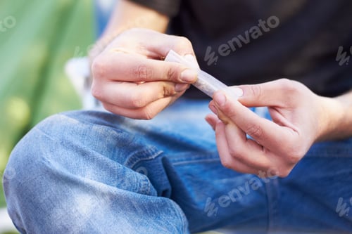Preview: Everything has a gateway. Shot of a unrecognizable person rolling a large marijuana joint.