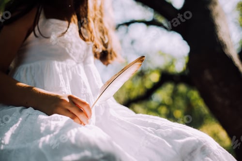 Girl Holding Feather in a Dreamy Outdoor Setting
