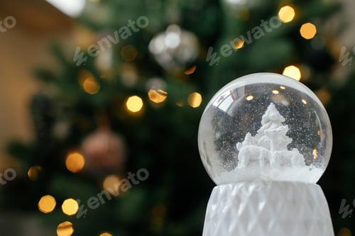 Preview: Stylish christmas snow globe against christmas tree in lights. Merry Christmas! Atmospheric winter
