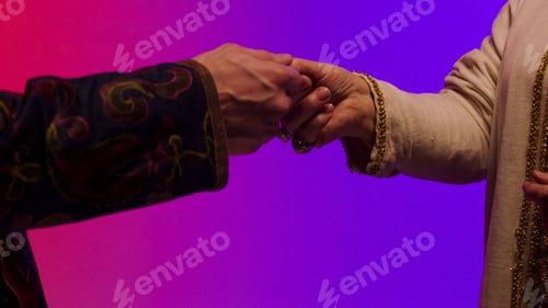Preview: Close up for eastern man hands giving big, black coin isolated on pink and blue background, making a