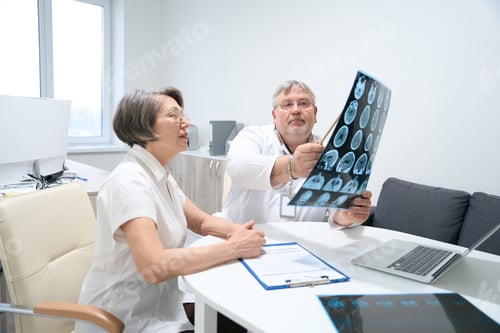 Preview: Elderly man and woman are studying MRI scans in diagnostic room