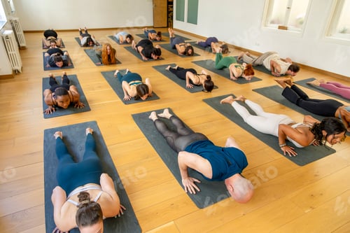 Preview: Yoga class practicing relaxation poses on mats in a spacious, sunlit studio.