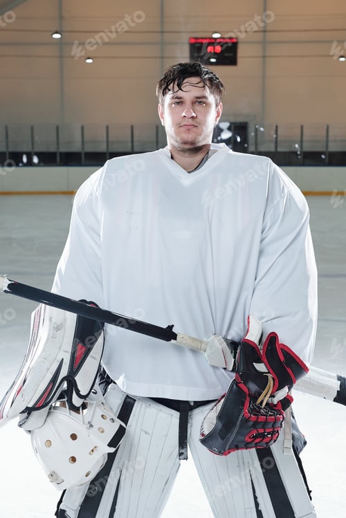 Preview: Young serious hockey player in sports uniform and gloves holding stick