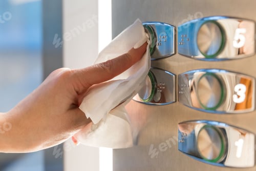 Preview: finger pressing button in elevator through a tissue to protect yourself from contact with covid-19