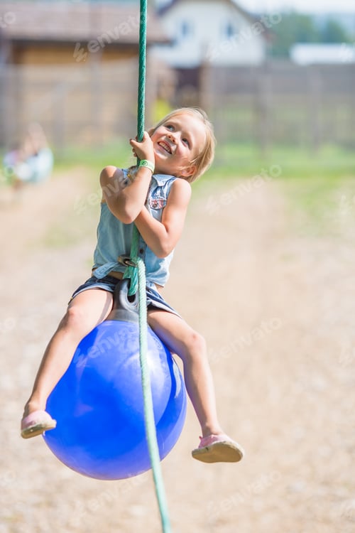 Preview: Adorable little girl having fun on a swing outdoors