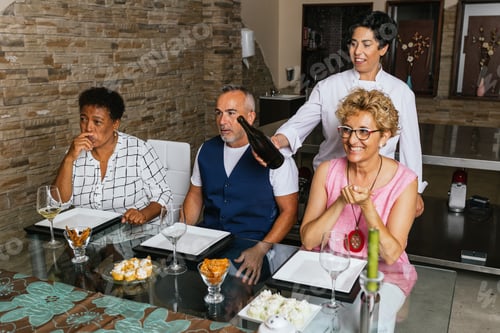 Preview: Chef pouring wine for guests during private dinner party