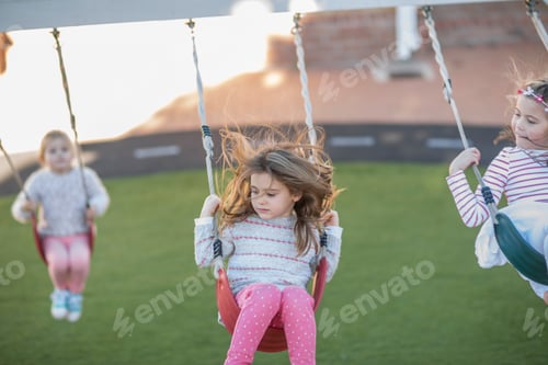 Preview: Children playing on swings at a playground.