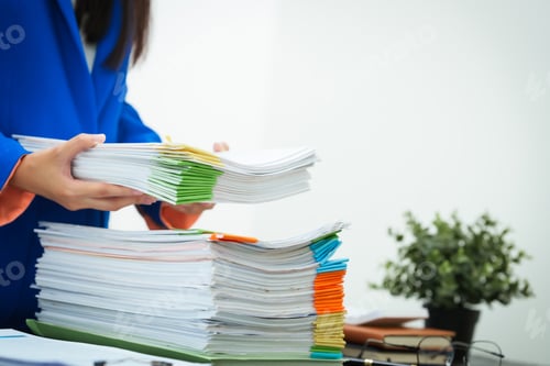 Preview: A young businesswoman works diligently her office desk, checking documents and analyzing finances