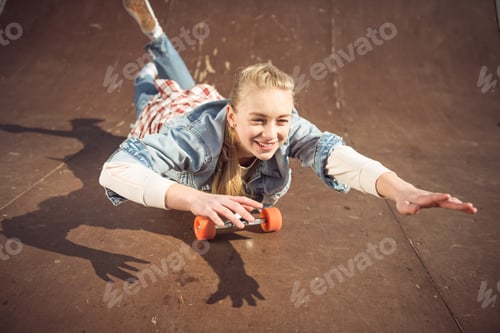 Preview: stylish hipster girl lying on skateboard at skateboard park