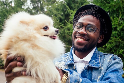 Preview: afro man hugging his fluffy spitz in park