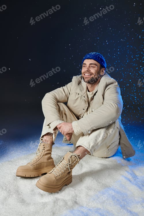 Preview: A handsome young man enjoys a playful moment in the snow, dressed in stylish winter fashion