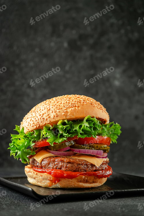 Preview: Burger with beef, cheddar cheese, onion,tomato,lettuce and pickled cucumber on slate plate.
