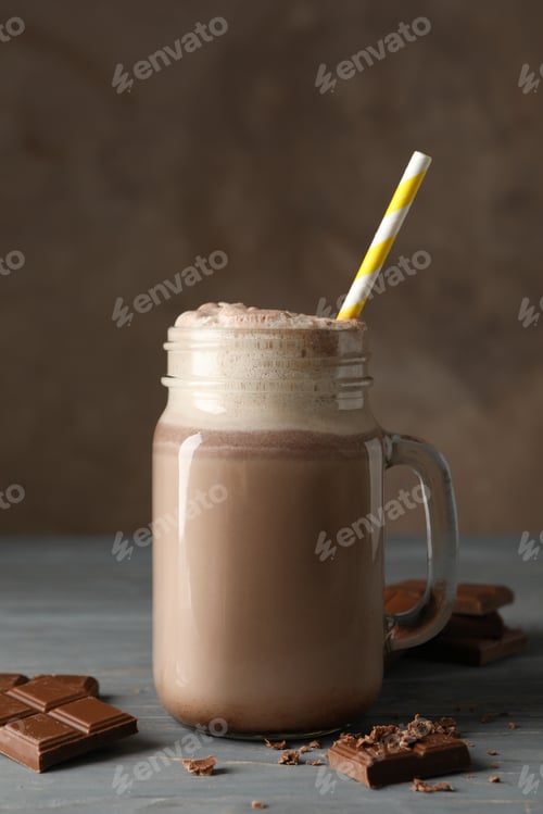 Preview: Glass of chocolate milkshake on wooden table. Summer drink