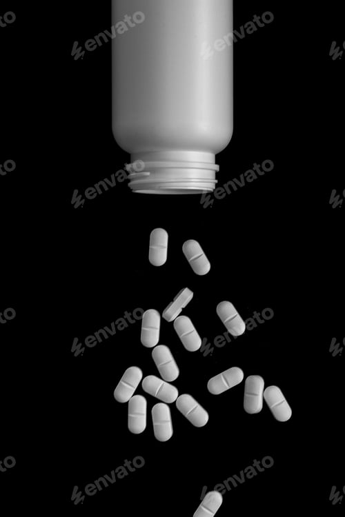 Preview: Vertical shot of a white pills box with many pills falling from it on a black background