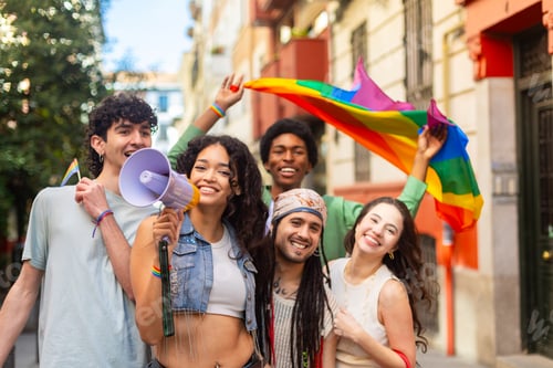 Preview: Young activists waving rainbow flag and using megaphone at pride parade