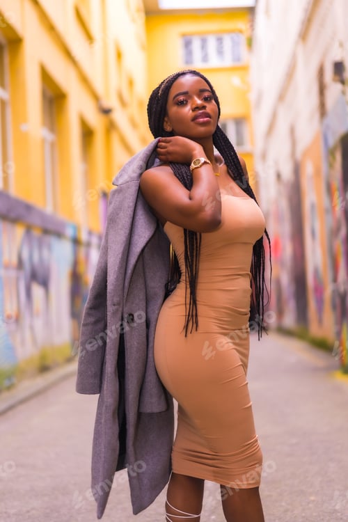 Preview: Trendy urban style with a black African girl in a cream colored dress on a city street