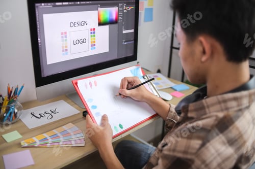 Preview: Creative Professional Comparing Color Swatches Against Digital Logo Design on Desktop Monitor
