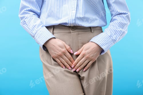 Preview: Woman suffering from cystitis symptoms on light blue background, closeup