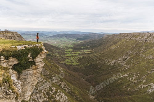 Preview: Man standing on cliff near valley