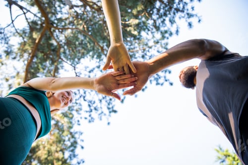 Preview: Three sportspeople join hands on top of each other, photo from below