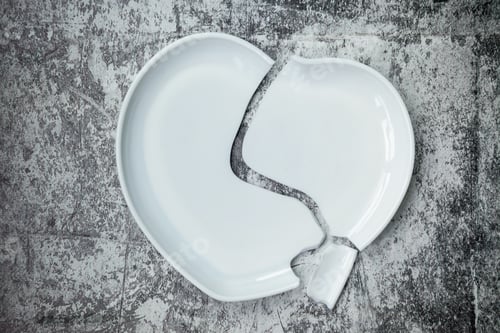 Preview: Backdrop of broken white ceramic heart-shaped plate on stone floor background