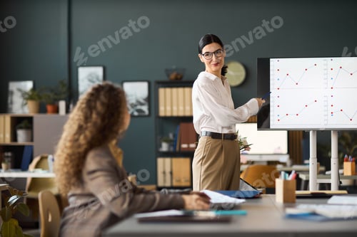 Preview: Caucasian Woman Presenting Business Data to Colleague in Office