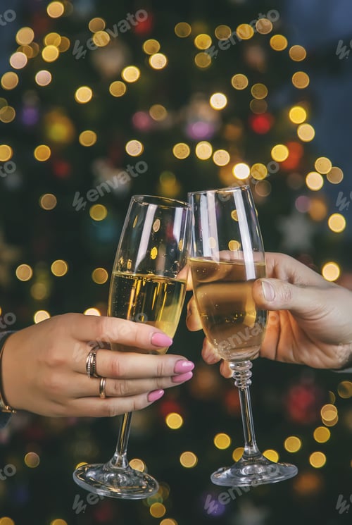 Preview: Champagne in hand against the background of the Christmas tree. People. Selective focus.