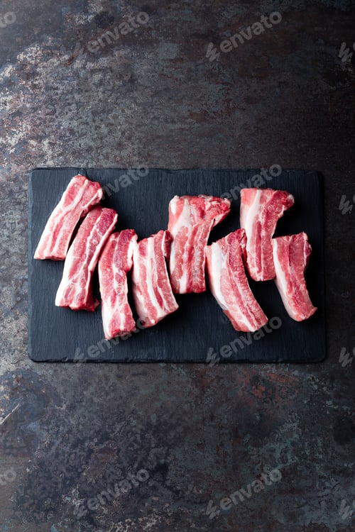 Preview: Raw uncooked pork ribs, fresh meat on dark metal background. Top view. Flat lay.