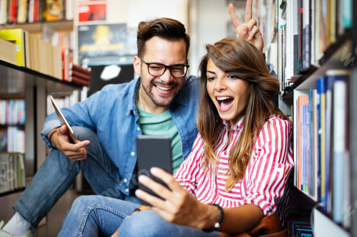 Preview: Happy young student couple taking a selfie in school library