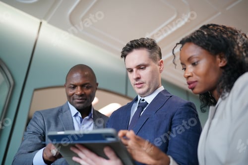 Preview: Image of young businessmen and colleague discussing document in laptop and touchpad at meeting