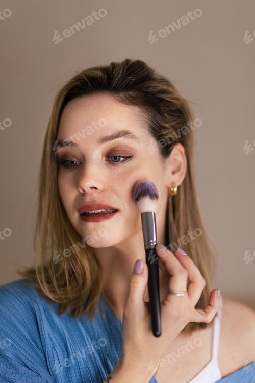 Preview: Young woman doing her make-up, with brush.