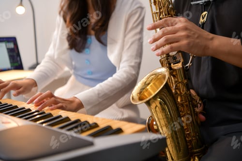 Preview: Two young Asian man and woman performing music indoors with keyboard and saxophone