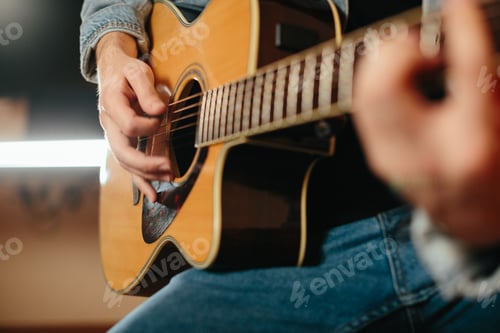 Preview: Young musician composing music playing acoustic guitar at home