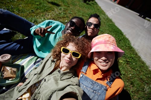 Preview: Young people taking selfie outdoors relaxing on grass in sunlight