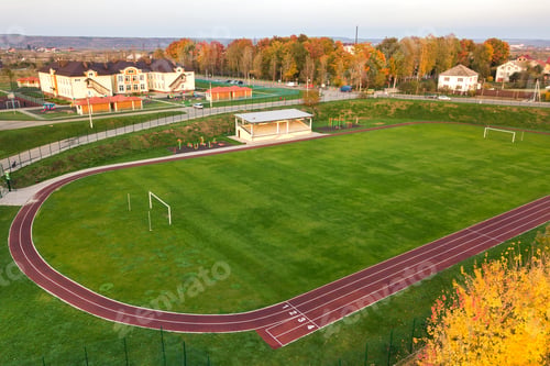 Preview: Aerial view of sports stadium with red running tracks and green grass football field.