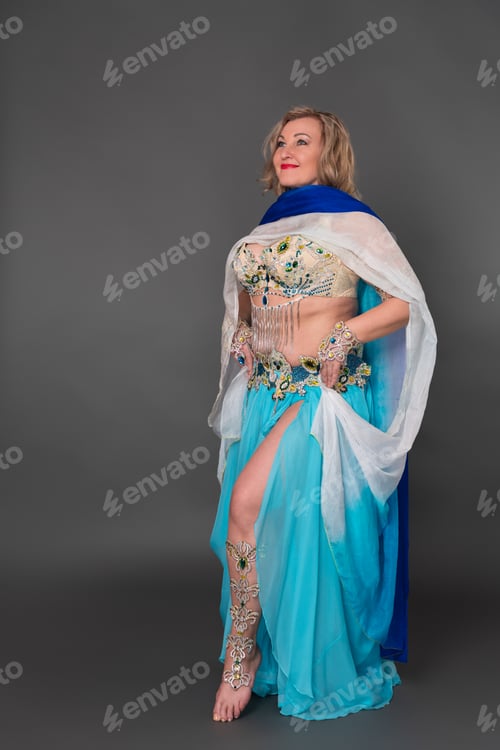 Preview: Fashionable woman model in stage costume - bra top and pareo, blue long skirt standing barefoot