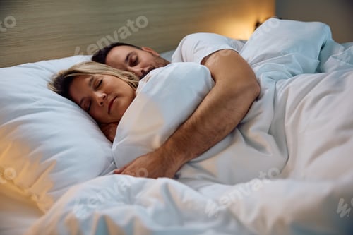Preview: Serene couple sleeping embraced in their bedroom.