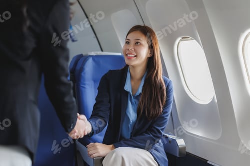 Preview: Businesswomen shaking hands while sitting in airplane cabin