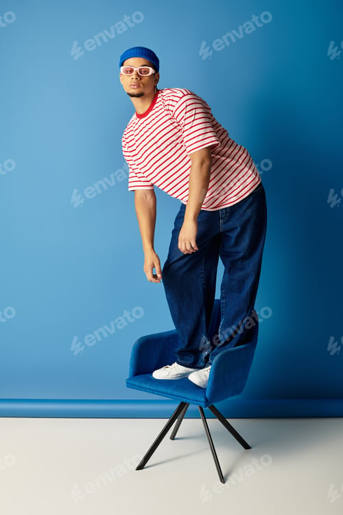 Preview: Stylish young man showcases trendy fashion on a vibrant blue background