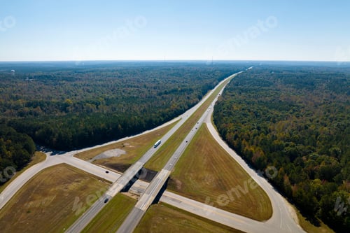 Preview: View from above of busy american highway with fast moving traffic between woods.
