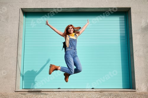 Preview: Happy woman jumping celebrating success against a light blue background
