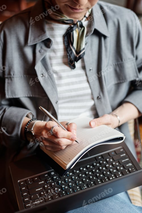 Preview: Businesswoman or freelancer with pen over blank page of copybook and keyboard