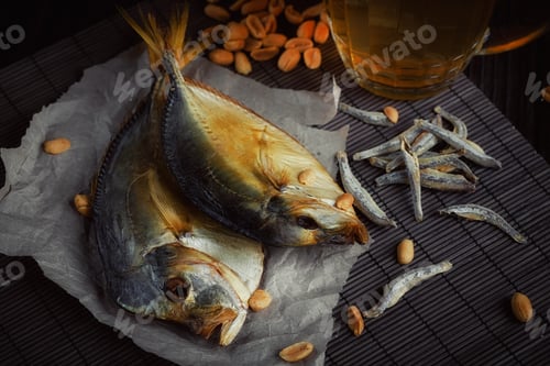 Preview: Beer and dried fish on dark wooden table.