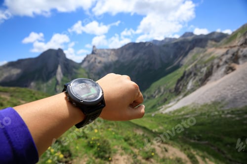 Preview: Hiker on high altitude mountain top checking the altimeter on the sports watch