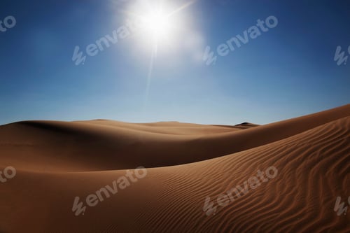 Preview: Sunlit desert dunes under a clear blue sky.
