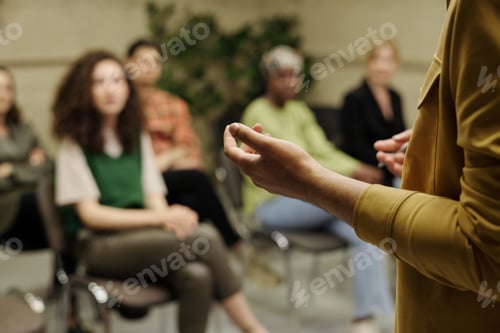 Preview: Hands of young business coach explaining information to group of employees