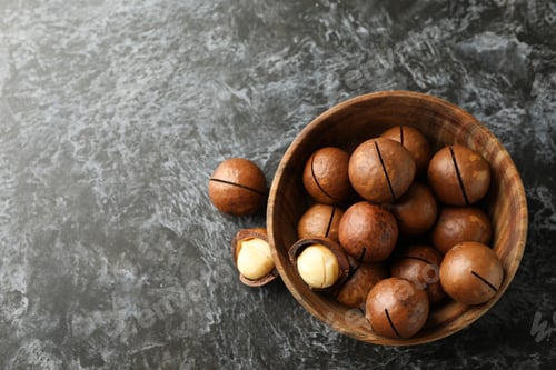 Preview: Bowl with tasty macadamia nuts on black smokey background